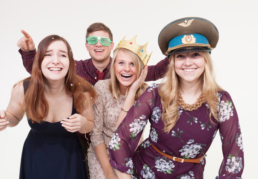 Gruppe junger Menschen posiert mit Accessoires vor Fotobox - Spaß Event in Berlin