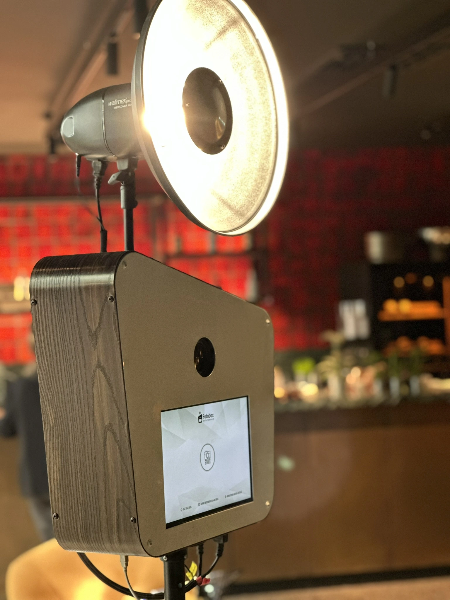 Edle Fotobox mit Holzakzenten und weißem Beauty-Dish-Reflektor in einer Berliner Event-Location für eine Firmenfeier.